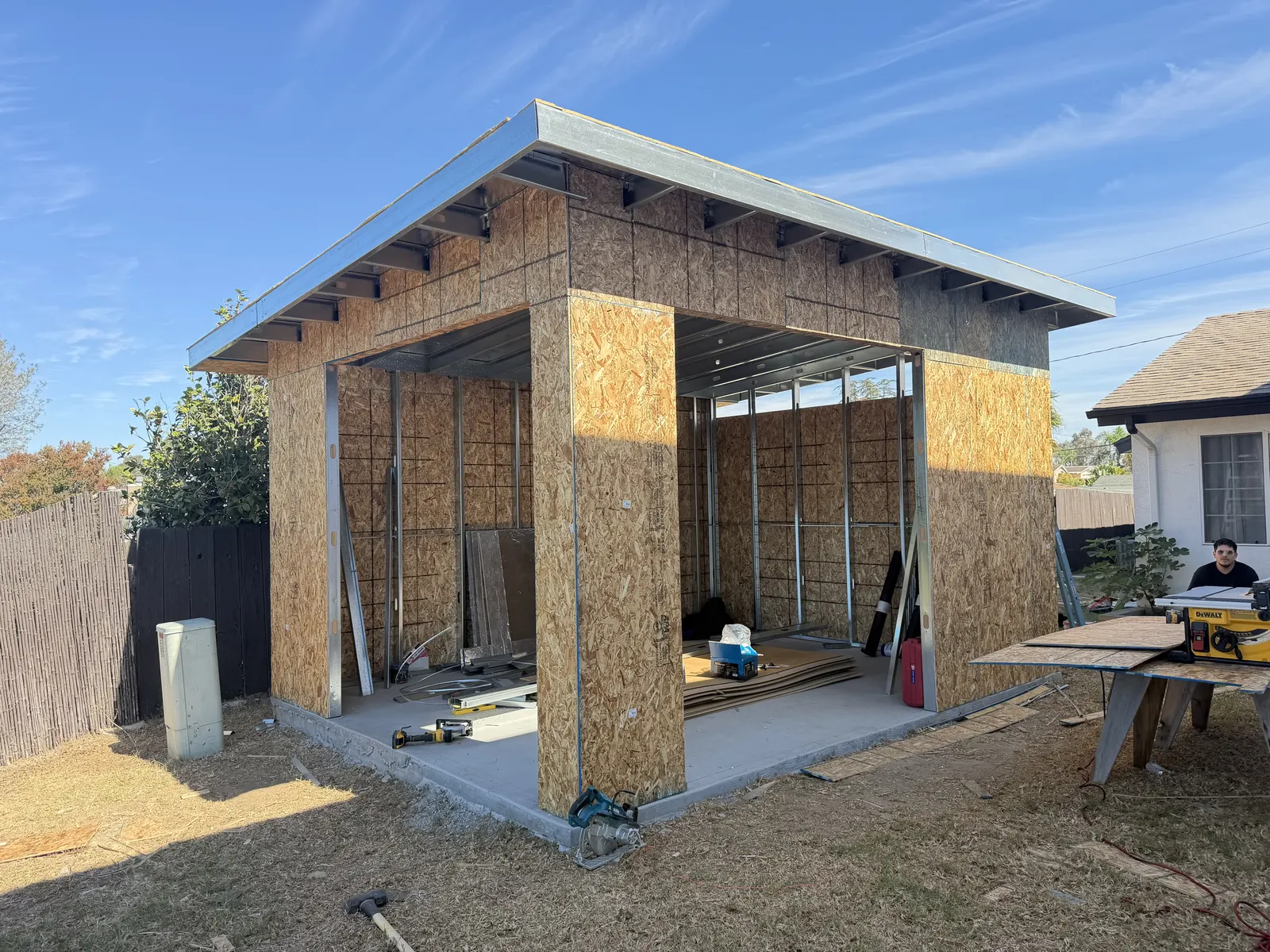 Front view of the same unfinished structure, showing metal framing inside two open bays and sheathed exterior walls