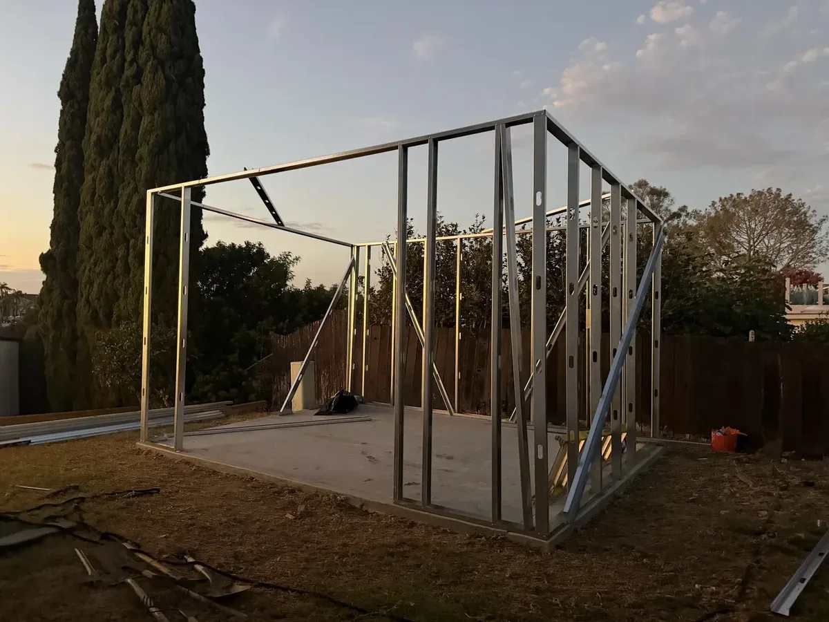 Metal wall frames standing on the slab with temporary diagonal bracing and no roof installed